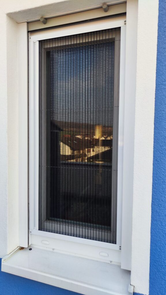 Fenster mit eingesetztem Insektenschutzgitter in weißem Aluminiumrahmen